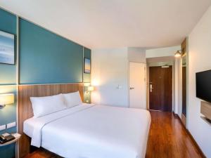 a bedroom with a white bed and a flat screen tv at Ibis Phuket Patong in Patong Beach +45 photos