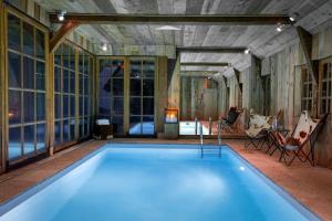 a swimming pool in a room with windows and a person sitting in chairs at La Chaumière in Honfleur