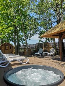 a hot tub on a deck with chairs and a umbrella at SCANDINAVIA Camping in Zator