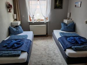 a bedroom with two beds with blue sheets and a window at Gasthaus & Pension Schmidt's in Haldensleben