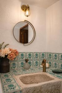 a bathroom with a sink with a mirror and flowers at Finca Altozano - Private pool in Valle de Abdalagís