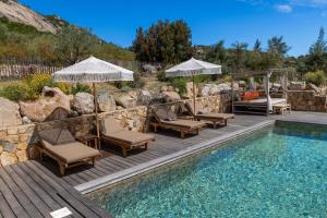 a deck with chairs and umbrellas next to a swimming pool at Villa Les Bergeries De Calvi in Calvi