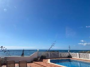 a swimming pool with chairs and the ocean in the background at Vila Monte Luz 3 in Ferragudo