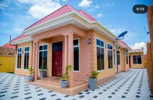 a rendering of a small yellow house with a red door at Vancovuer homes in Dodoma