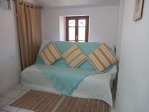 a couch with four pillows on it with a window at La Petite Maison de Caractere Catalan in Argelès-sur-Mer