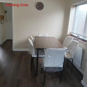 ein Esstisch mit Stühlen und eine Uhr an der Wand in der Unterkunft Double bedroom with shared facilities in Lexden