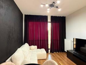 a living room with a white couch and red curtains at MC Residence Łomża in Łomża