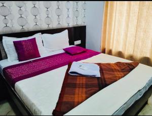 a bedroom with a bed with white sheets and purple pillows at Alaknanda lodge in Varanasi