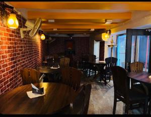 a restaurant with tables and chairs and a brick wall at Alaknanda lodge in Varanasi
