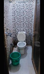 a bathroom with a toilet and a green bucket at Alaknanda lodge in Varanasi