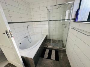 ein weißes Badezimmer mit Badewanne und Dusche in der Unterkunft SimPhil Haven in Bulawayo