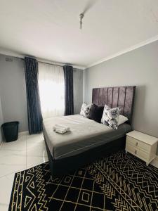 ein Schlafzimmer mit einem großen Bett und einem Teppich in der Unterkunft SimPhil Haven in Bulawayo