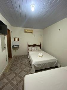 a bedroom with two beds and a tv in it at Pousada Orienttal in Santarém