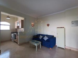 a living room with a blue couch and a kitchen at OrientalCoast Marsa Alam Private Beach in Quseir