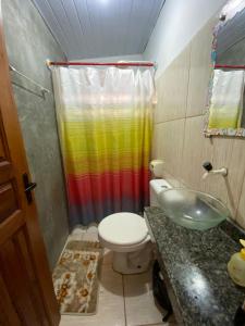 a bathroom with a rainbow shower curtain and a toilet at Pousada Orienttal in Santarém