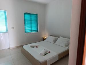 a white bedroom with a bed with two candles on it at Jasmine Apartments in Velipojë