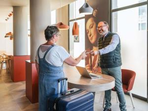 two men shaking hands in front of a table with a laptop at ibis Styles Le Mans Gare Sud in Le Mans
