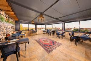 a restaurant with tables and chairs and large windows at Cappadocia Tughan Stone House in Uçhisar