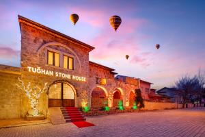 a tucan stone house with hot balloons in the sky at Cappadocia Tughan Stone House in Uçhisar