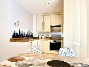 a kitchen with white cabinets and a table and chairs at Stay in Stratford in London +36 photos