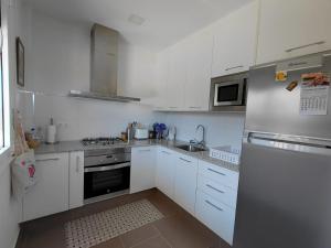 a kitchen with white cabinets and a stainless steel refrigerator at Al Eu in Ribeira