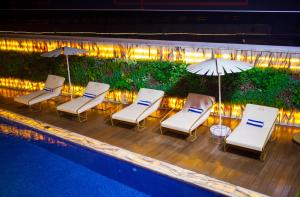 a group of chairs and umbrellas next to a pool at The Vynyard, Accra in Accra