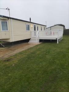 a mobile home with a porch and a deck at Seaside Stay in Camber
