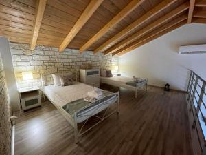 a bedroom with two beds and a brick wall at Celeste Syvota in Syvota