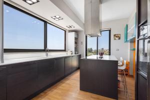 a kitchen with black cabinets and large windows at Villa Panorama Kalathas - 4 Bedrooms Near beach in Chorafakia