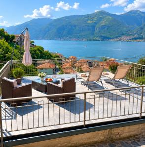 a balcony with chairs and a table and an umbrella at Dudi Jolie Maison - Jacuzzi in Lezzeno