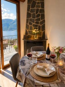 a dining table with wine glasses and a fireplace at Dudi Jolie Maison - Jacuzzi in Lezzeno