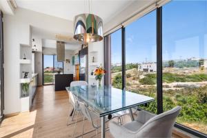 a dining room with a glass table and white chairs at Villa Panorama Kalathas - 4 Bedrooms Near beach in Chorafakia