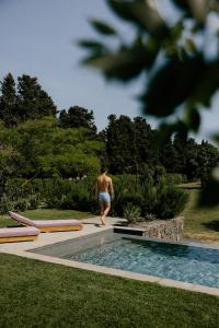 a man walking next to a swimming pool at Scorzamara Country Lodges - Retreats with Private Pool or Jacuzzi in Carlentini
