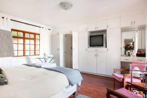 a white bedroom with a bed and a tv at Your homely experience in Paarl