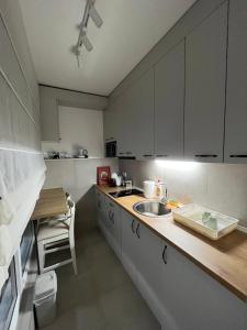 a kitchen with white cabinets and a sink and a table at Porodična oaza Vrnjačka Banja in Vrnjačka Banja