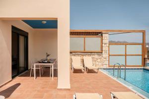 a patio with a table and chairs next to a pool at Corali Villas - Seaview, Private Pools, 450 to Beach in Kolymvari
