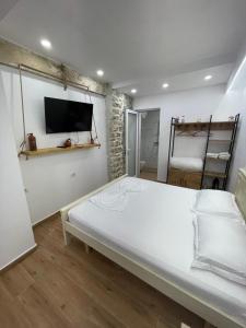 a bedroom with a large bed with a tv on the wall at Saranda Garden Rooms in Sarandë