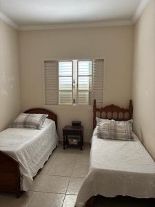 a bedroom with two beds and a window at Iluminarch Home in Passa Quatro