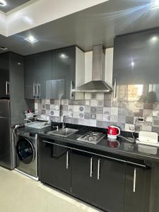 a kitchen with black cabinets and a sink and a dishwasher at JULYA appartement centre in Tangier