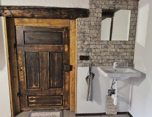 a bathroom with a wooden door and a sink at Drevenica M&P 2 in Bešeňová