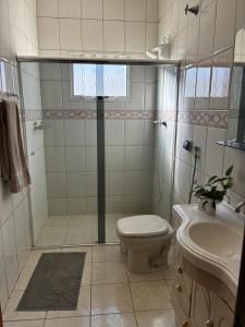 a bathroom with a shower and a toilet and a sink at Iluminarch Home in Passa Quatro