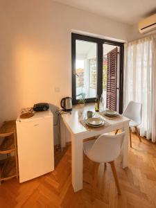ein weißer Tisch und Stühle in einem Zimmer mit Fenster in der Unterkunft Aurra Studio in Budva