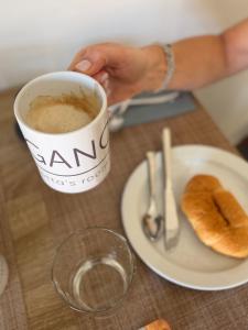 a person holding a cup of coffee and a plate of food at ELEGANCE Calasetta's Rooms in Calasetta +12 photos