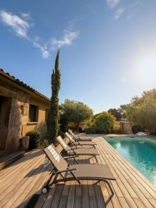 a row of lounge chairs on a wooden deck next to a swimming pool at Villa Sébastien by Intendance Excellency in Zonza