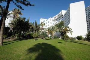 a park with palm trees in front of a building at Kenzi Solazur in Tangier