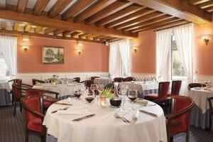 uma sala de jantar com mesas e cadeiras brancas em Hôtel Du Labrador em Saint-Benoît-sur-Loire