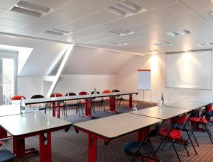 a room with tables and chairs and a projection screen at Logis Hôtel Restaurant Du Labrador in Saint-Benoît-sur-Loire