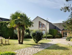 a house with a palm tree in the yard at Logis Hôtel Restaurant Du Labrador in Saint-Benoît-sur-Loire