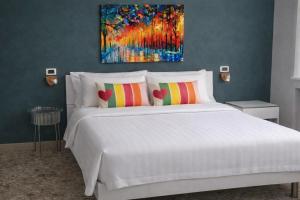 a bedroom with a white bed with a painting on the wall at B&B Residence Armonia Sulmona in Sulmona