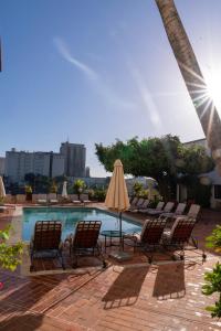 a pool with chairs and an umbrella and a table and chairs at Hodelpa Nicolás de Ovando in Santo Domingo